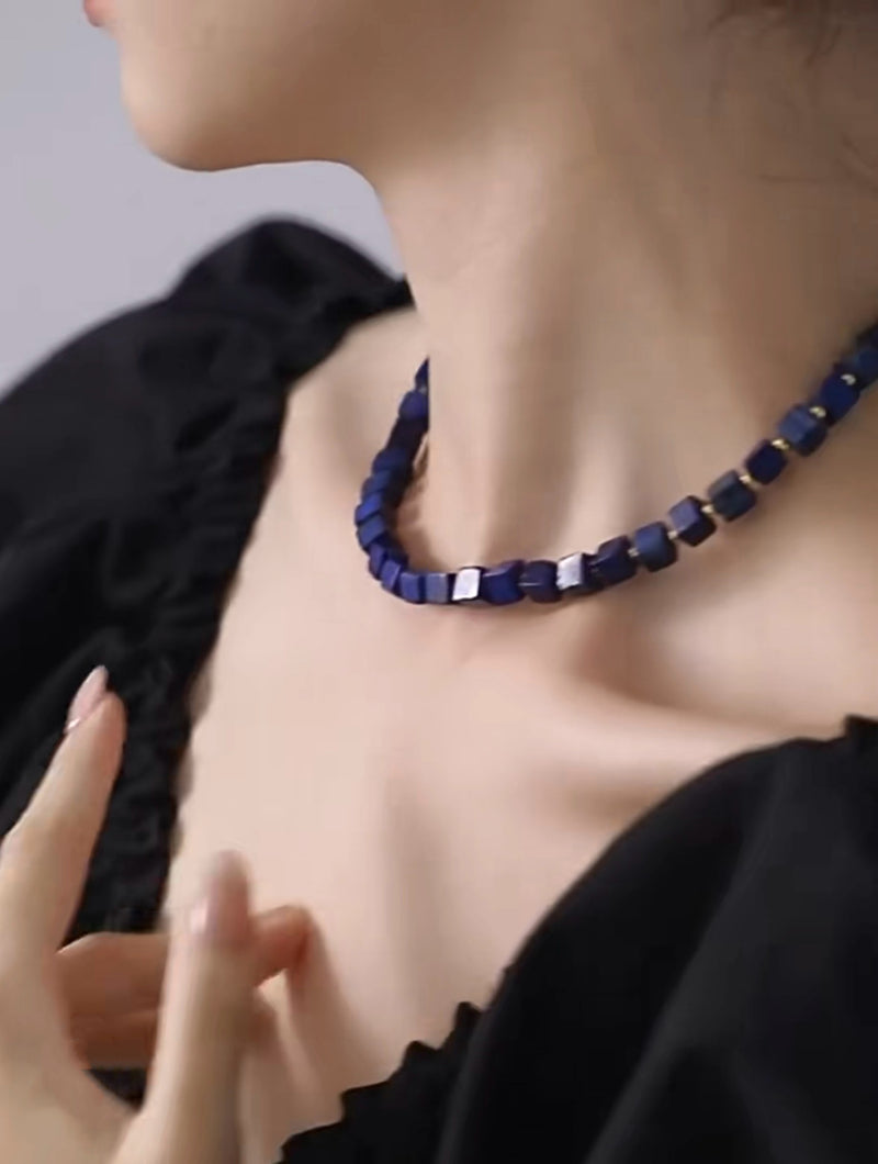 Deep blue cube bead necklace for spiritual healing and chakra balance, worn elegantly on model.