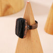 Black tourmaline ring on wooden display, healing crystal jewelry for protection and grounding