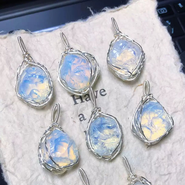Handmade moonstone pendants with wire-wrapped settings, featuring iridescent blue and white hues for spiritual healing and chakra balance.