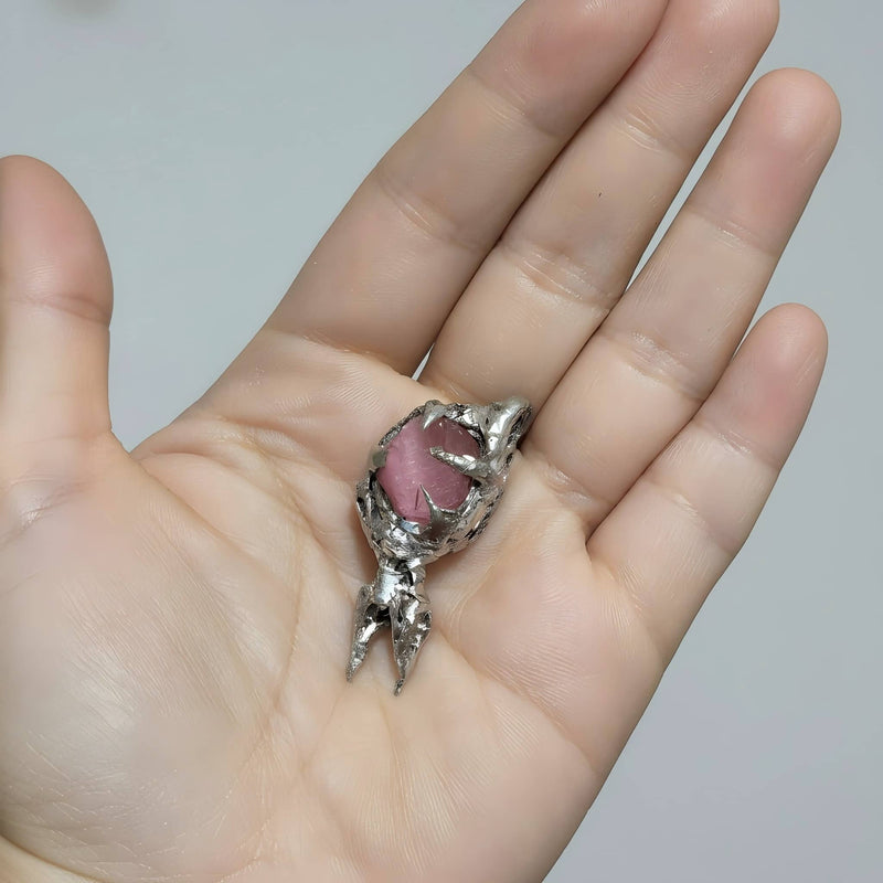 Hand holding a silver dragon claw pendant with pink rose quartz crystal, healing gemstone jewelry