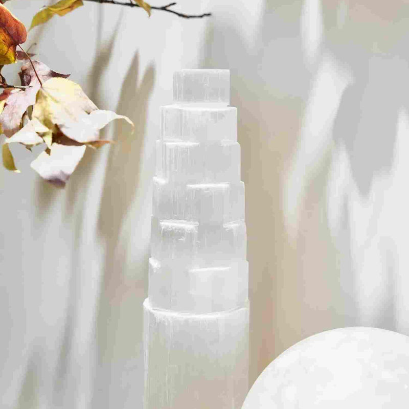 Clear selenite tower crystal for spiritual healing and energy cleansing, with autumn leaves and soft light