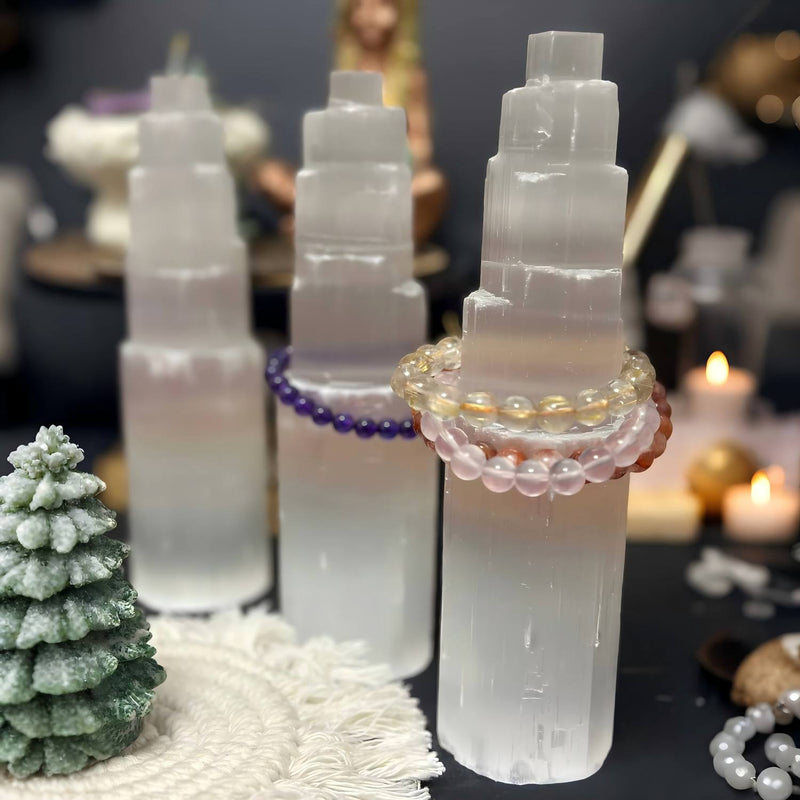 Selenite towers with gemstone bracelets, crystal healing setup for spiritual wellness and chakra balance