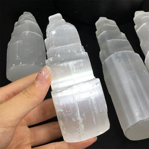 Hand holding natural selenite tower crystal for spiritual healing and protection, ideal for chakra alignment and anxiety relief
