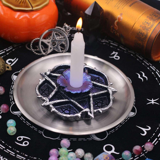 Pentagram candle holder with purple flower base, lit white candle, surrounded by crystals and spiritual decor