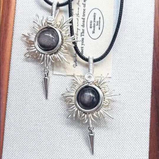Handmade sunburst pendant with black crystal, silver wire wrap, and spike charm on black cord