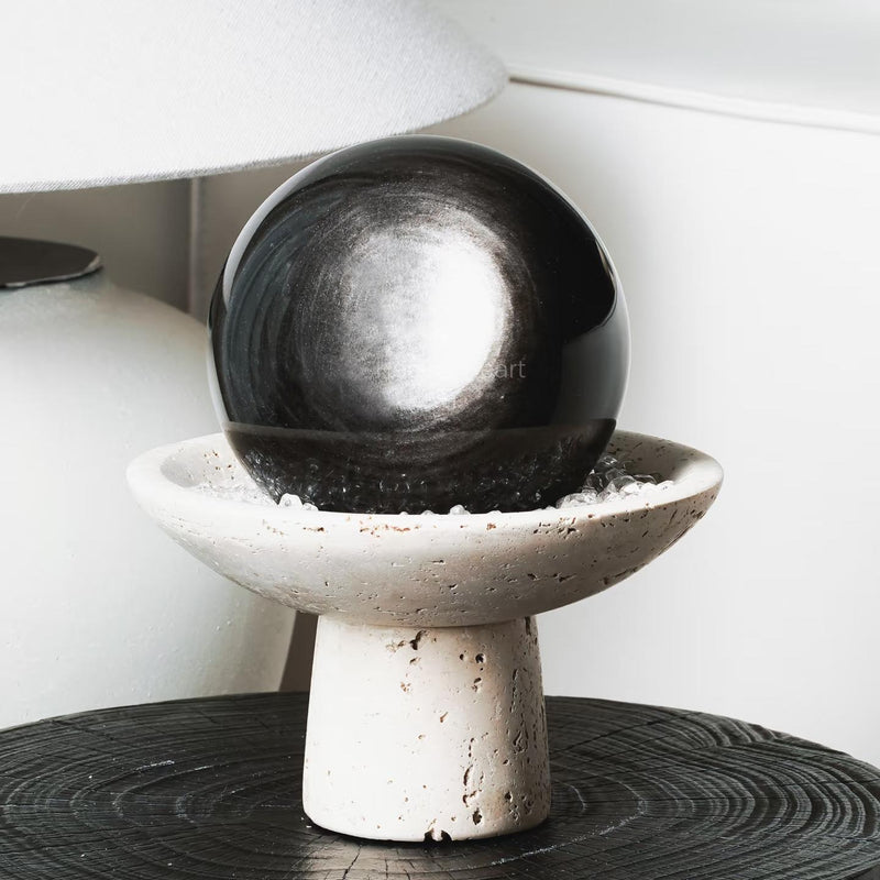 Polished black crystal sphere on textured stone pedestal, ideal for healing and spiritual decor