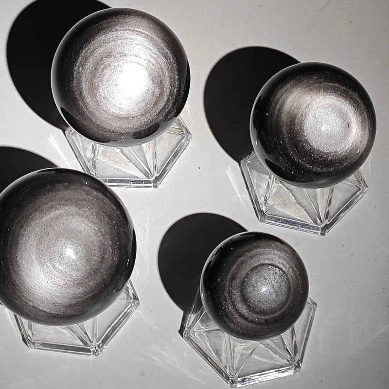 Shiny silver hematite spheres on crystal stands for spiritual healing and protection