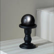 Shiny black crystal sphere on matte black pedestal for spiritual healing and protection