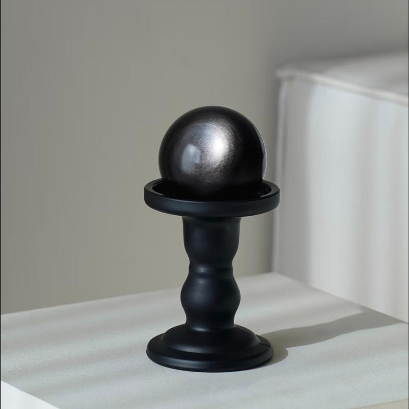 Shiny black crystal sphere on matte black pedestal for spiritual healing and protection