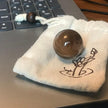Smooth brown crystal sphere on floral pouch, ideal for chakra healing and spiritual growth