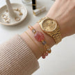 Hand wearing gold watch with pink crystal bracelet, gemstone jewelry for spiritual healing and protection