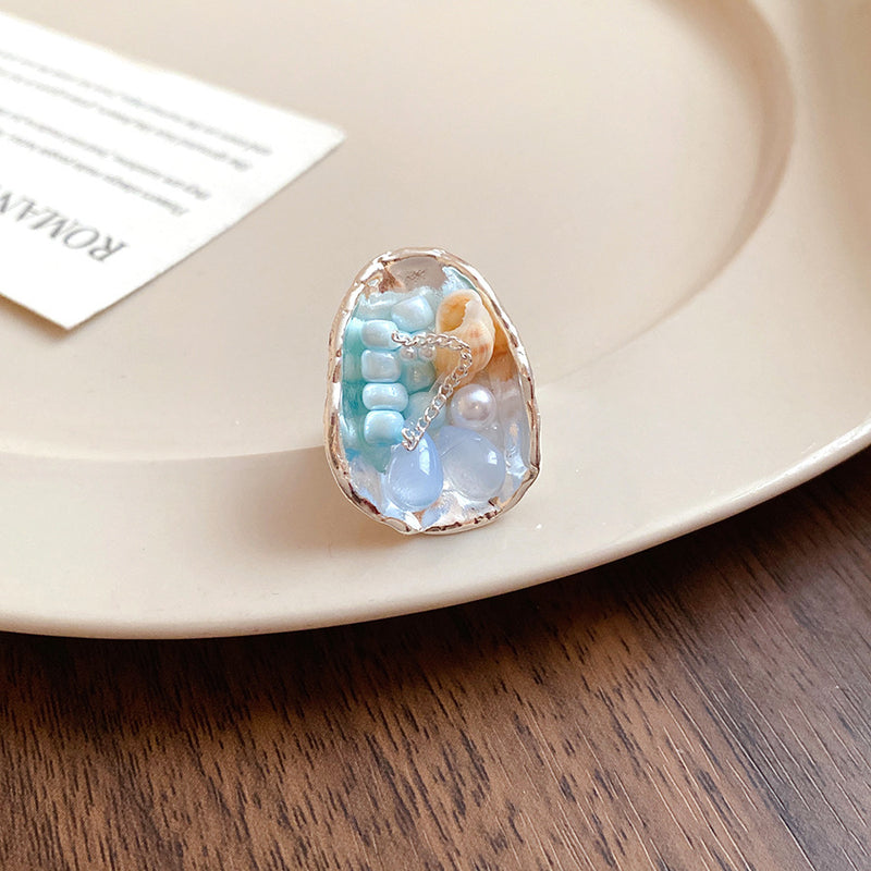Handmade resin ring with blue beads, pearl, and seashell, set in silver-toned frame for spiritual jewelry lovers