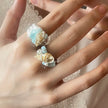 Hand wearing two seashell and aquamarine gemstone rings, boho beach jewelry for spiritual healing