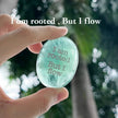 Hand holding engraved aquamarine crystal with 'I am rooted, But I flow' for spiritual growth and calm