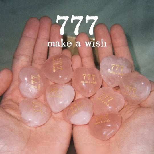 Hands holding rose quartz hearts engraved with 777 make a wish, spiritual healing crystals for love and manifestation