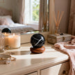 Black onyx crystal sphere on wooden stand with candle, jewelry, and diffuser for spiritual decor and protection