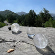 Clear quartz crystal spheres on rocky ledge with mountain view, ideal for spiritual healing and energy work