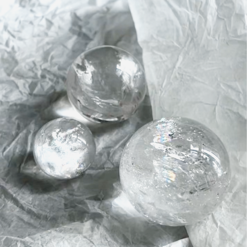 Clear quartz crystal spheres for healing, protection, and spiritual growth on crinkled paper