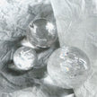 Clear quartz crystal spheres for healing, protection, and spiritual growth on crinkled white paper