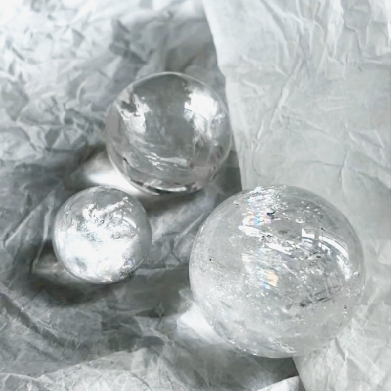 Clear quartz crystal spheres for healing, protection, and spiritual growth on crinkled white paper