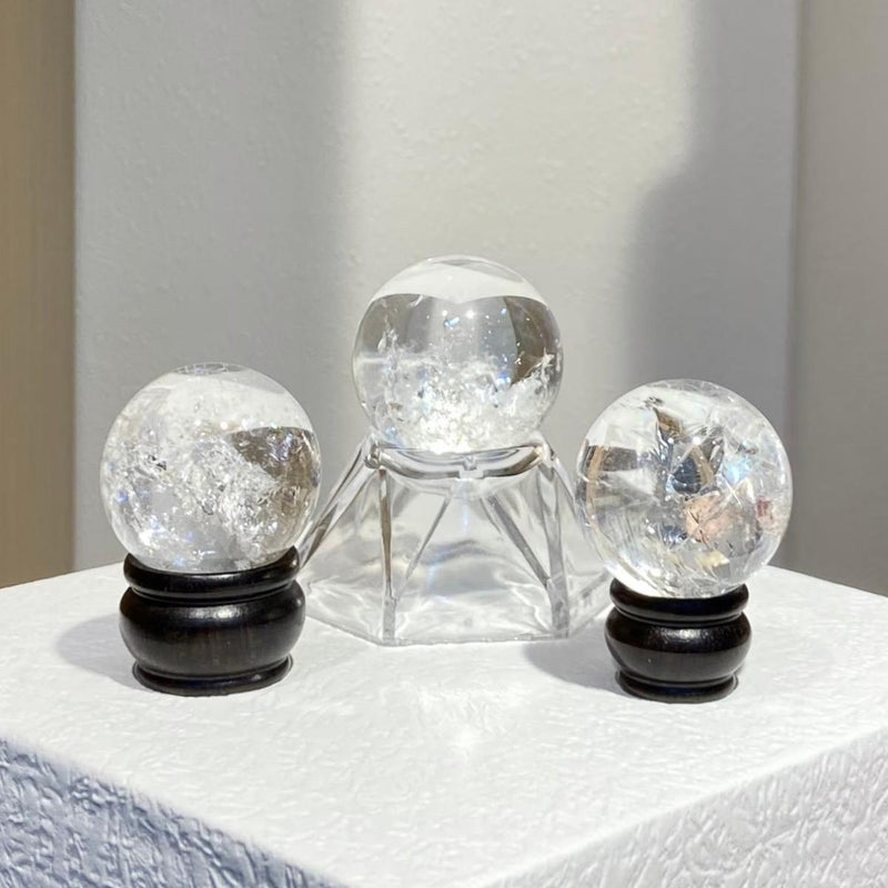 Clear quartz crystal spheres on wooden and glass stands for spiritual healing and energy work