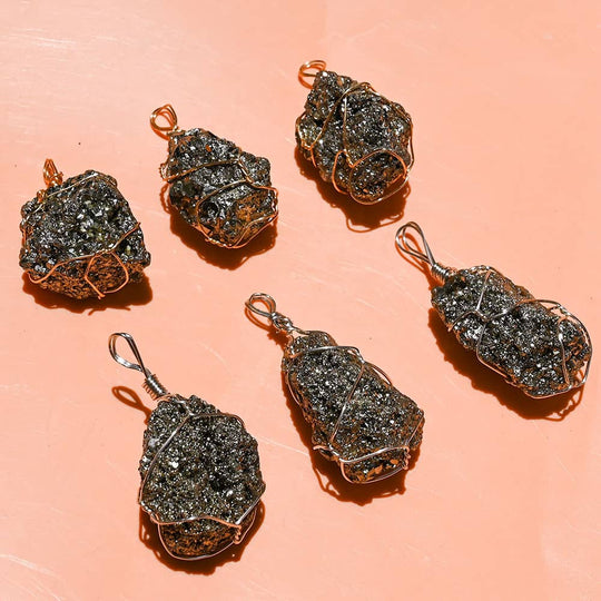 Wire-wrapped raw black crystal pendants for protection and spiritual growth on peach background