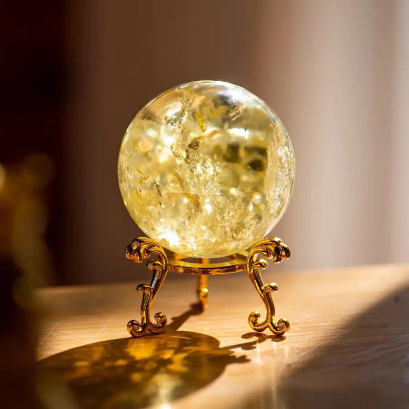 Golden citrine crystal sphere on ornate stand for spiritual healing and positive energy