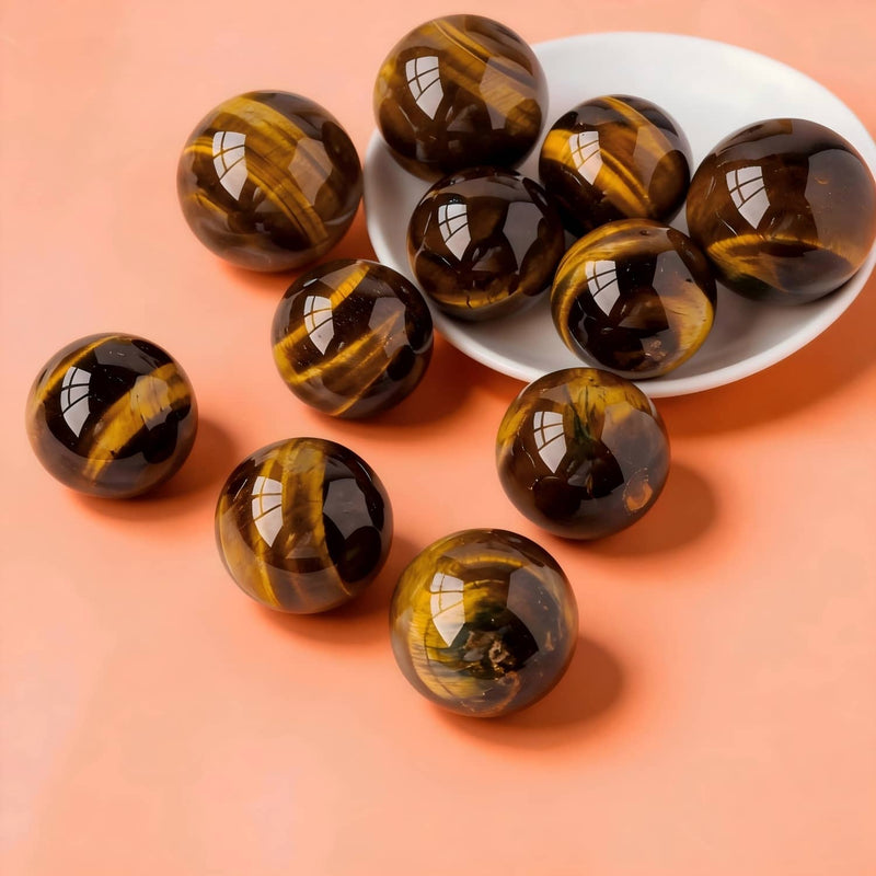 Polished tiger eye crystal spheres for protection and spiritual growth, displayed on a white dish against peach background