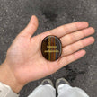 Hand holding engraved tiger eye stone with 'Solvitur ambulando' for spiritual healing and grounding