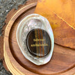 Tiger eye crystal with 'Solvitur ambulando' engraving in abalone shell, natural wood and autumn leaf setting